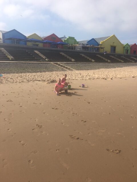 Beach with kids playing in the sand and beach huts